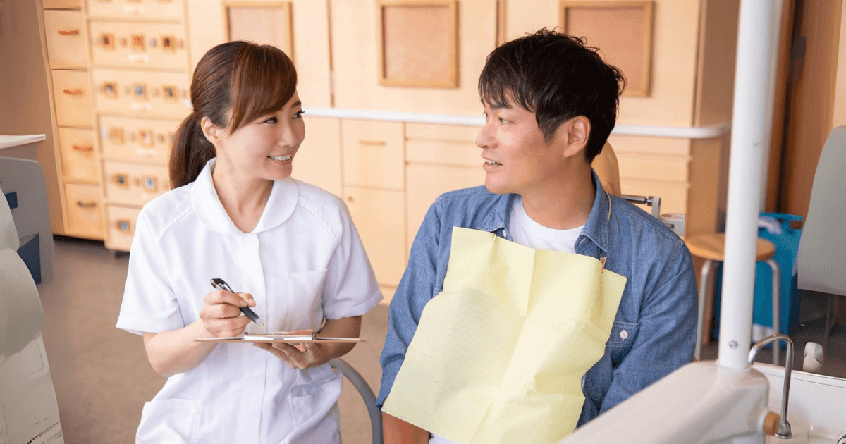 歯科衛生士に症状を伝える男性患者の様子