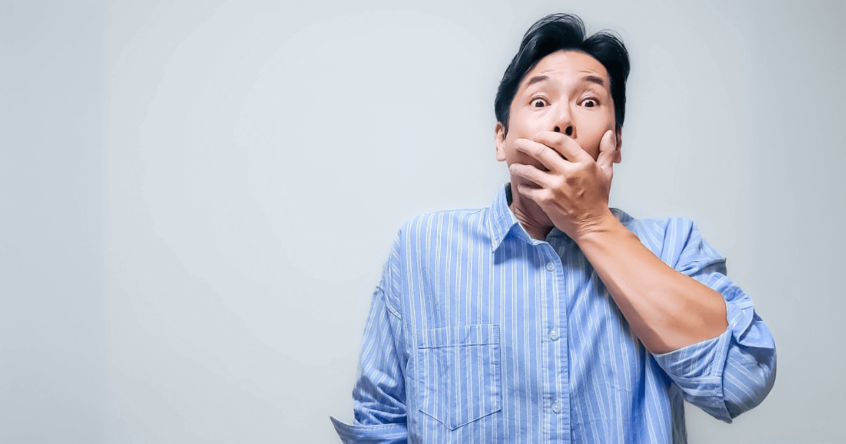 突然の歯のトラブルに驚く表情の男性の写真