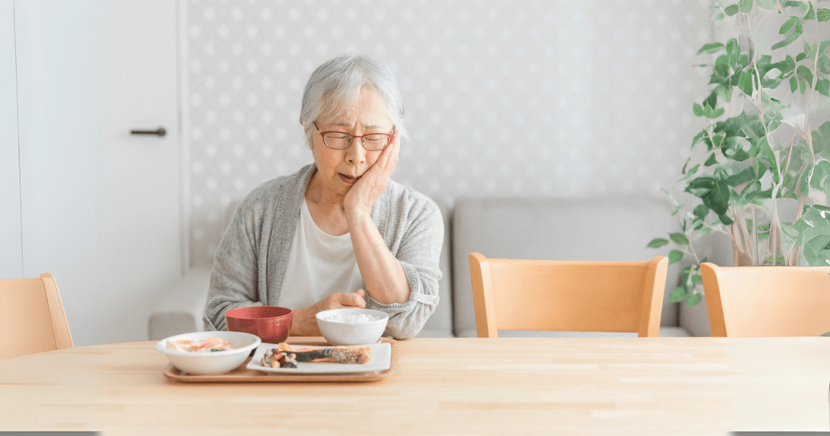 歯の痛みで食事に困っている高齢女性の様子