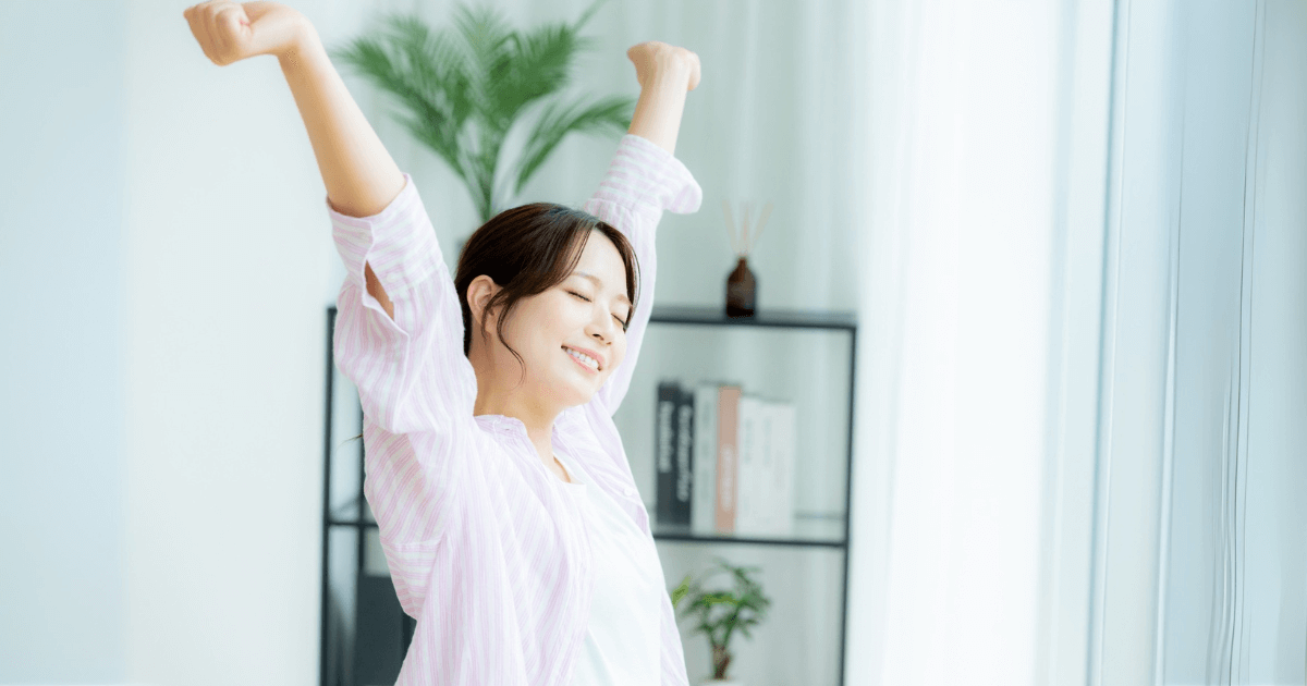 朝の光の中でストレッチをして笑顔を見せる女性