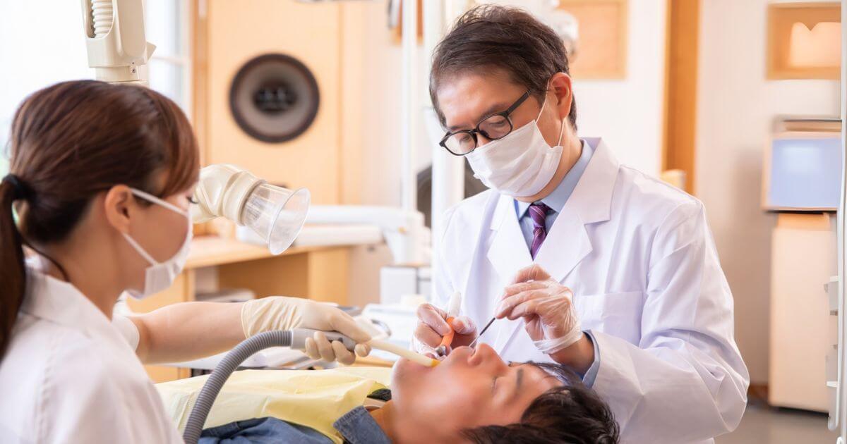 歯科医院で治療を受ける男性患者と歯科医師