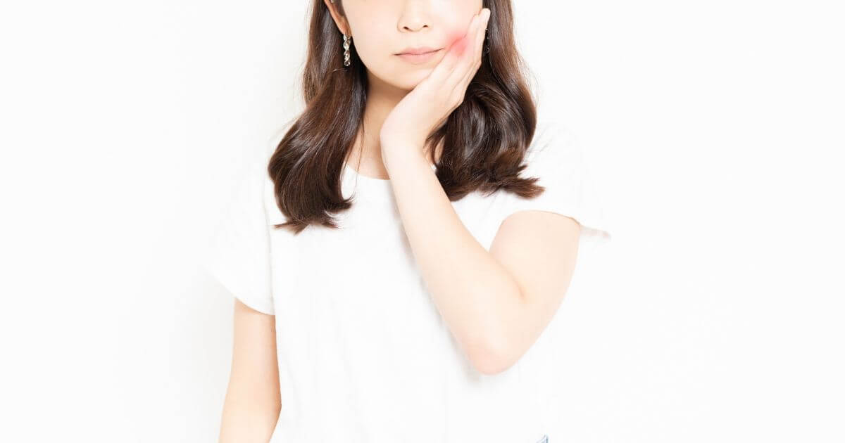 歯の痛みで頬を押さえる女性