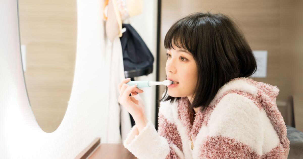 電動歯ブラシで歯を磨く女性