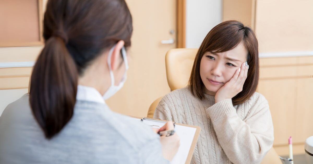 歯の痛みを訴えて歯科医に相談する女性