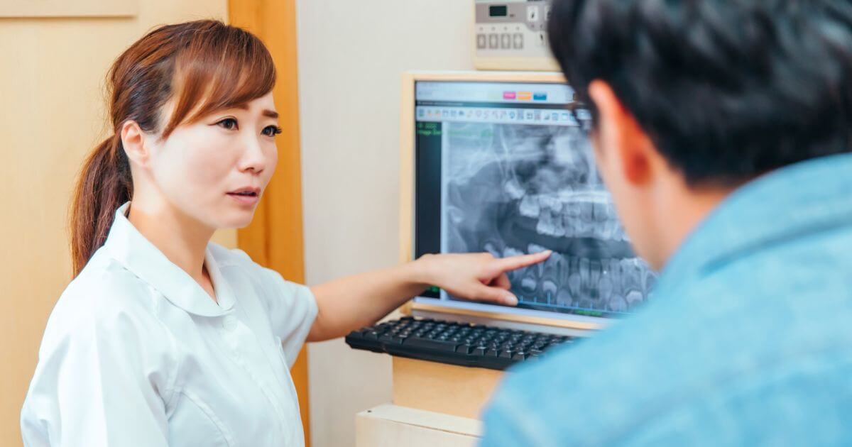 歯科医師が患者にレントゲン画像を見せながら説明している様子