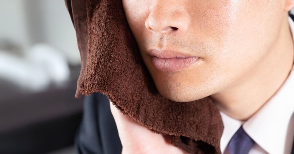 歯の痛みに対し、頬を冷やして応急処置をしている男性の画像