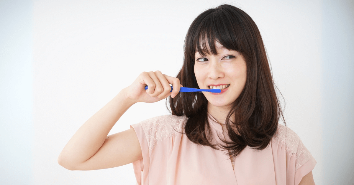 歯みがきをしながら笑顔を見せる女性