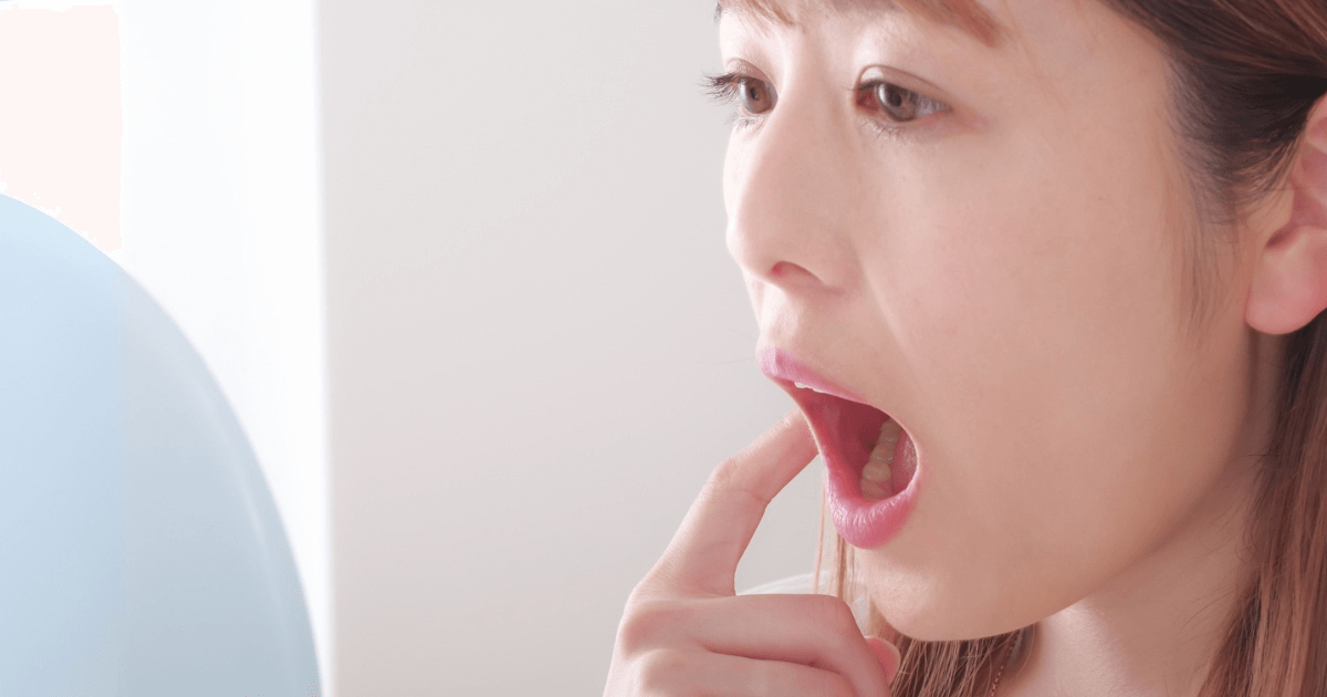 鏡を見ながら歯の横を確認する女性