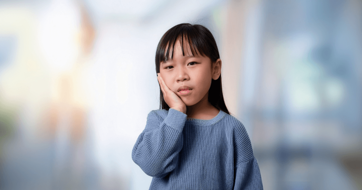 歯の痛みで頬を押さえる子供
