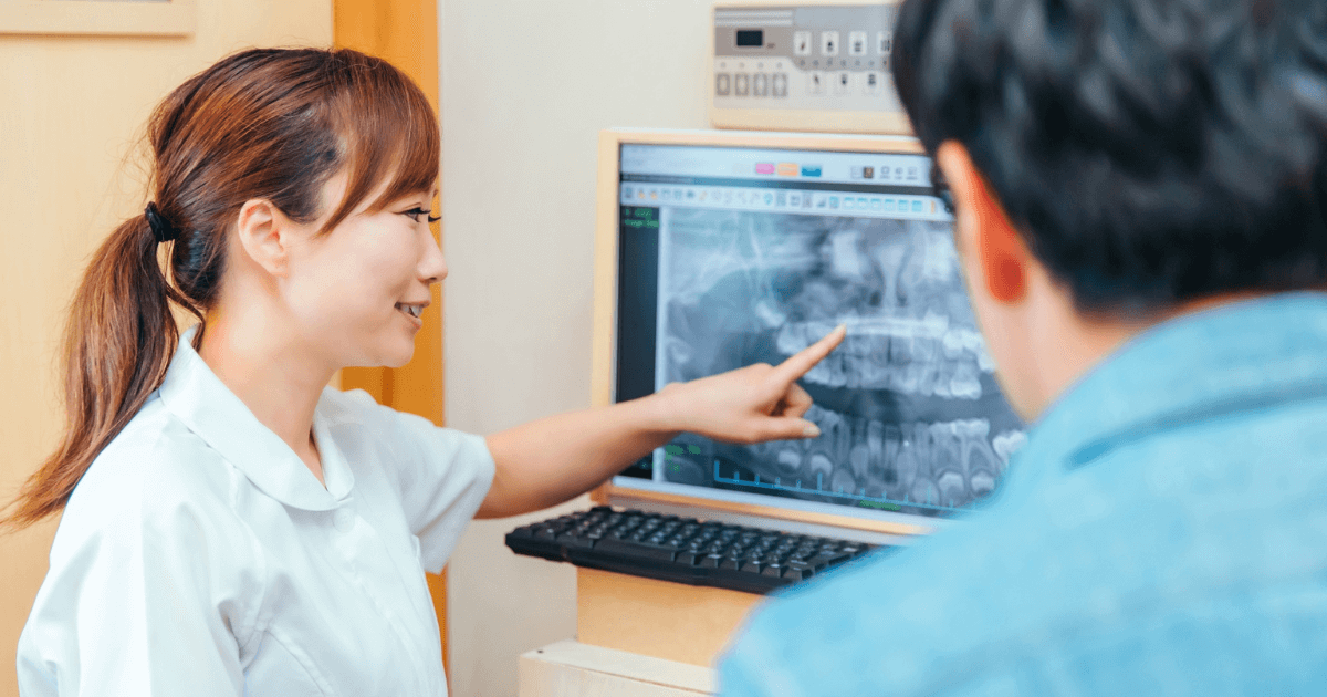 歯科医が患者にレントゲン画像を見せながら説明している様子