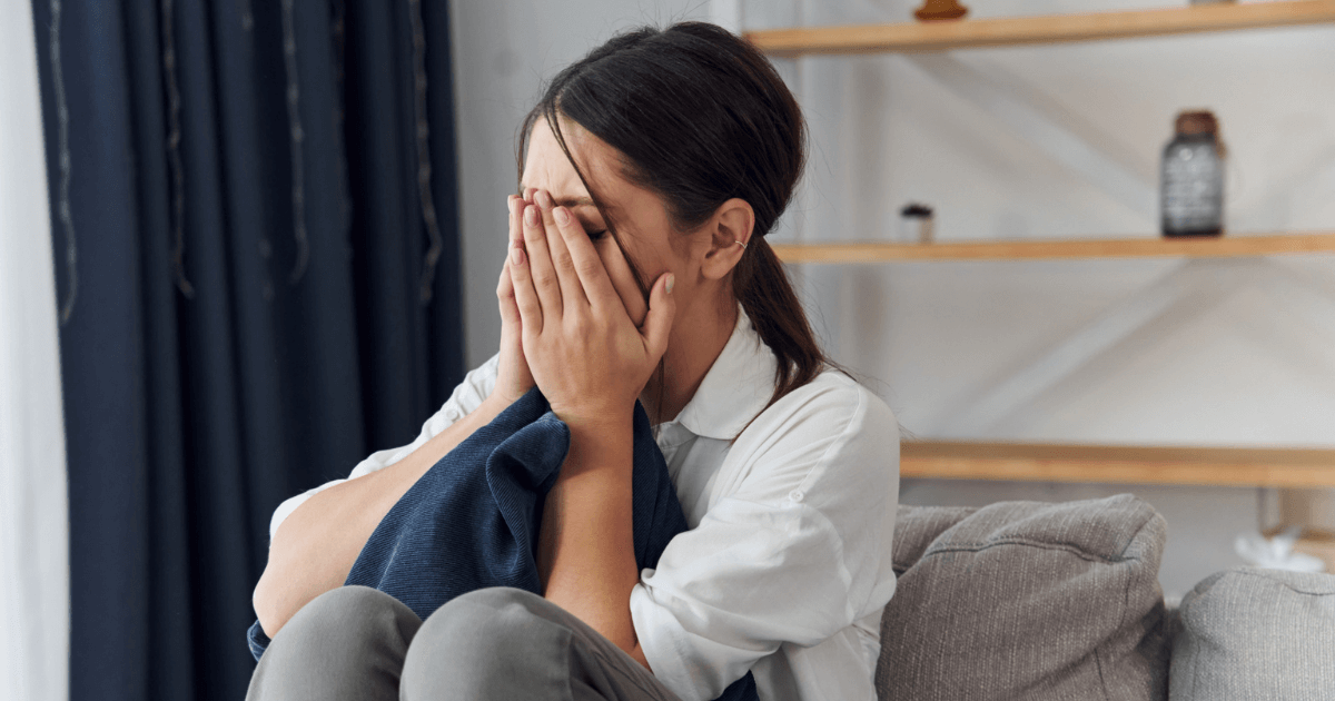 ソファで顔を覆い歯の状態を恥ずかしがる女性