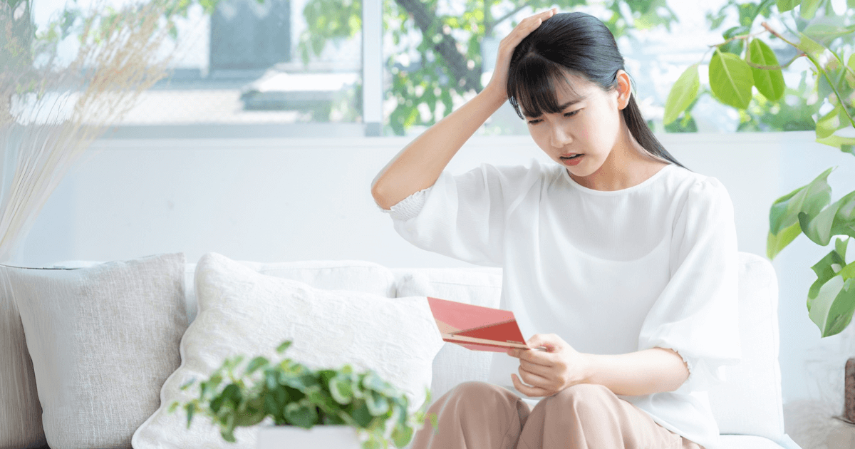 歯科治療費を前に悩む女性の写真