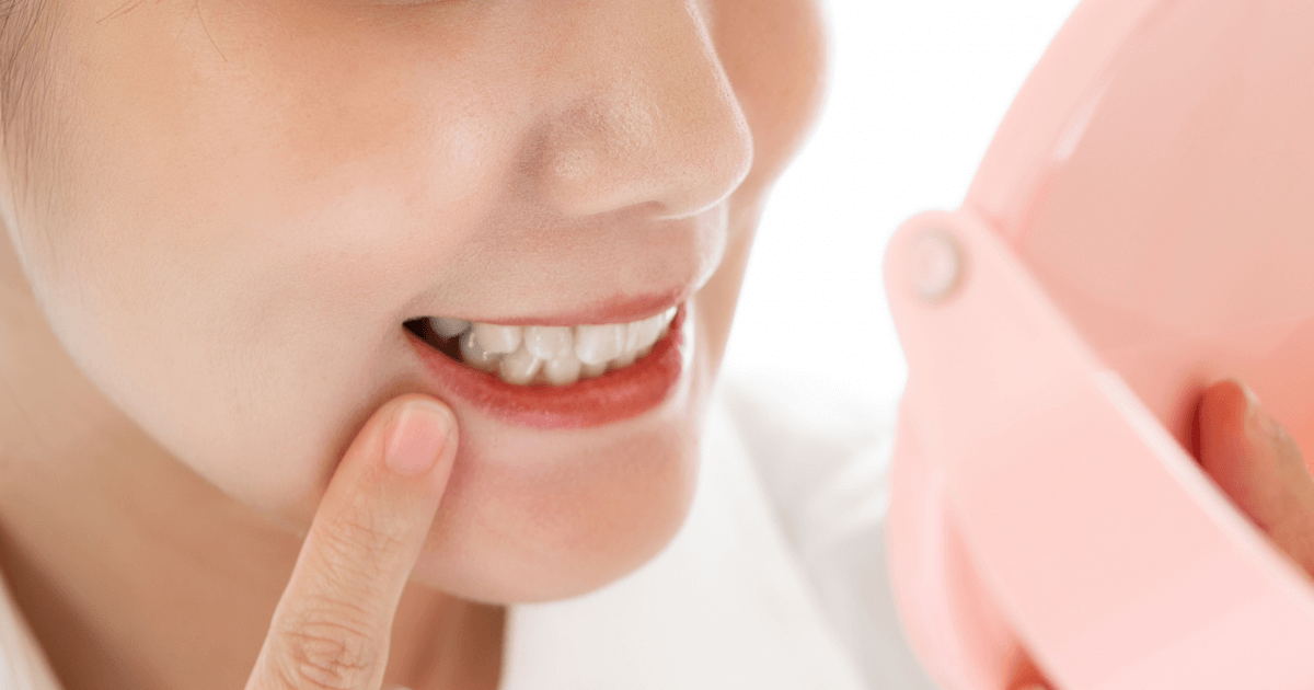 鏡を見ながら歯を指で確認する女性