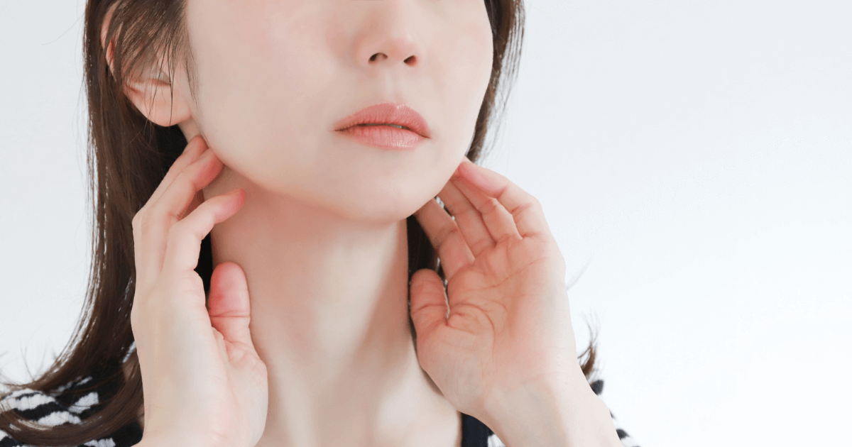 顎に手を当てて歯や顎の不調を感じている女性