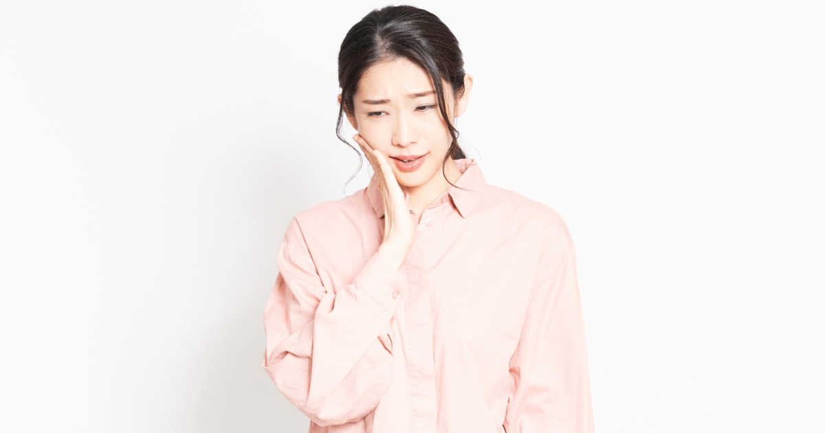 歯の痛みで頬を押さえる女性