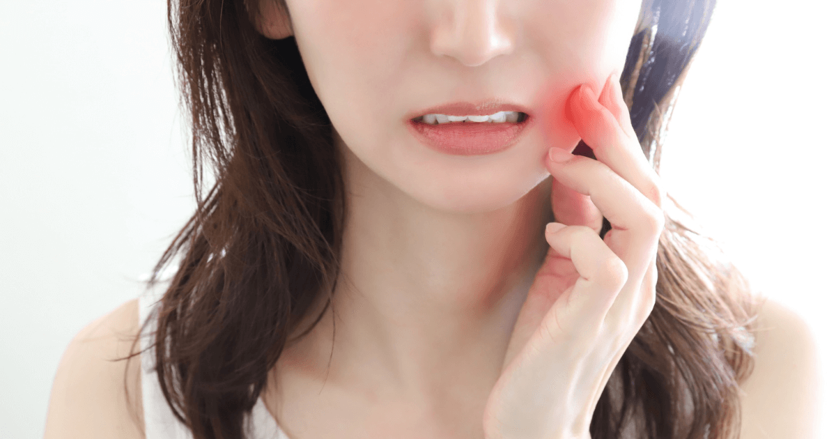 歯の痛みで頬を押さえる女性