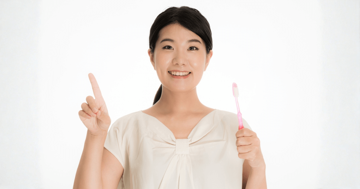 抜歯後の痛みをやわらげるためのケア方法を示す女性のイメージ（歯ブラシを持って笑顔）