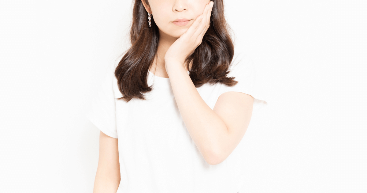 歯の痛みや違和感を感じて頬に手を当てる女性