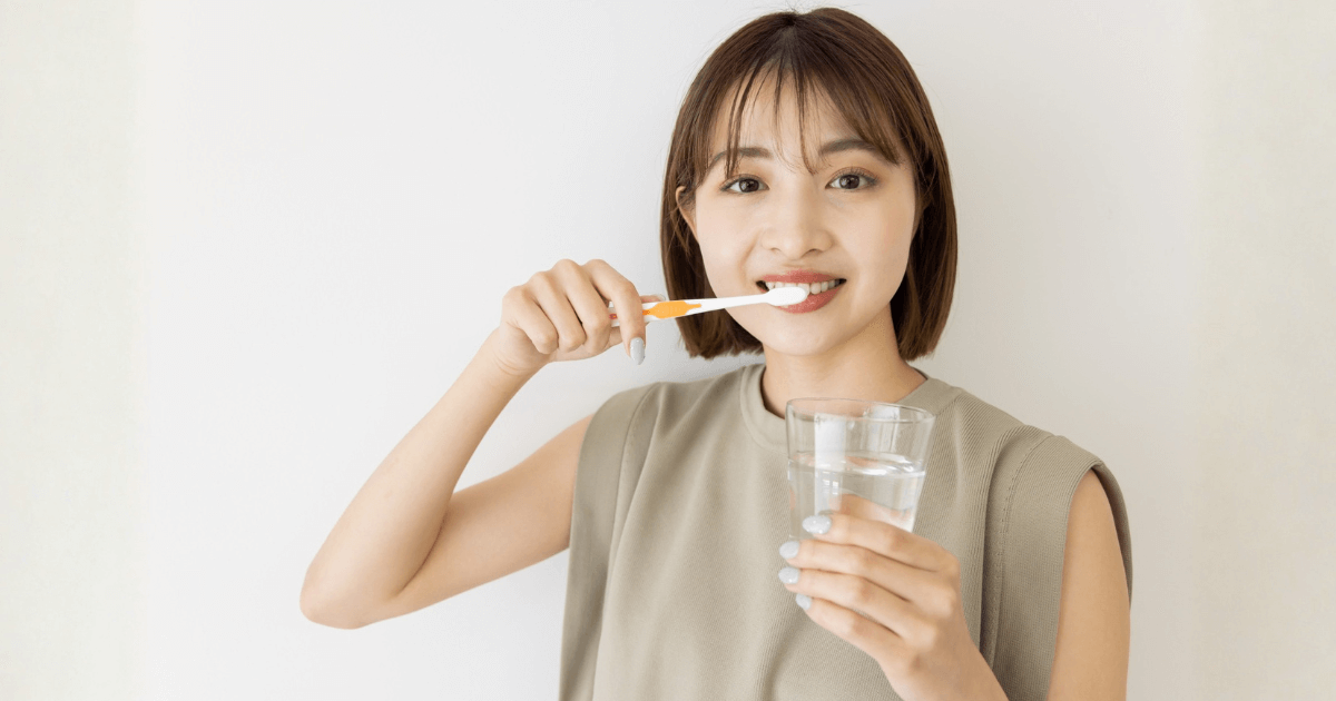 歯みがきと水でうがいをする女性のイメージ