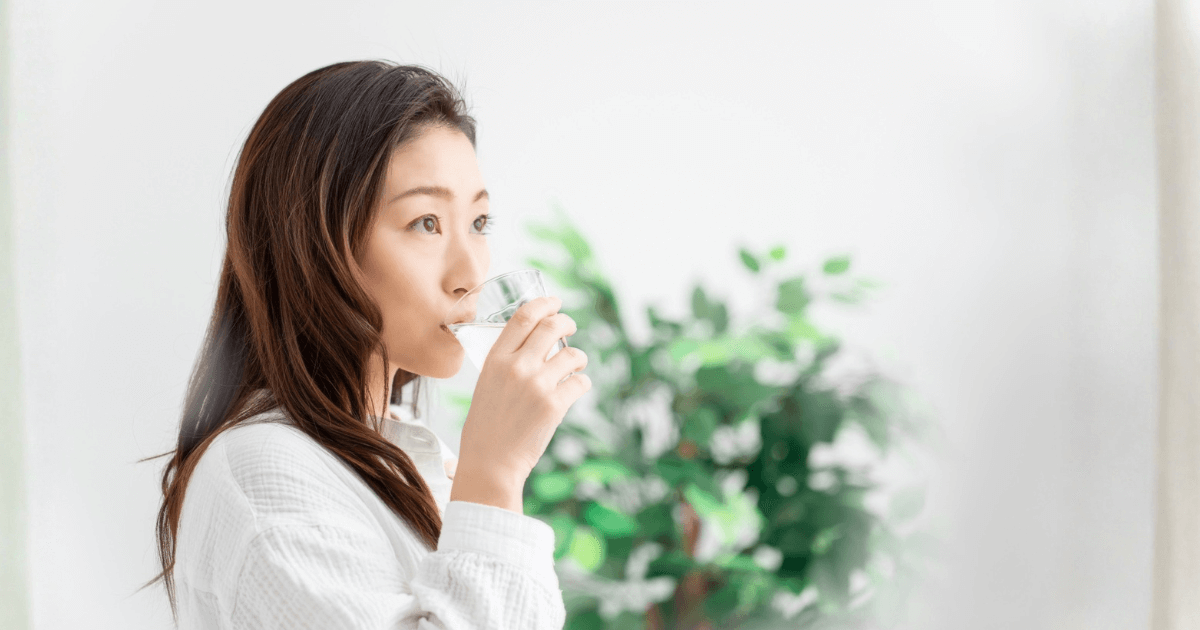 コップの水でうがいをしている女性。頬の腫れや口内の炎症に対する自宅ケアのイメージ。