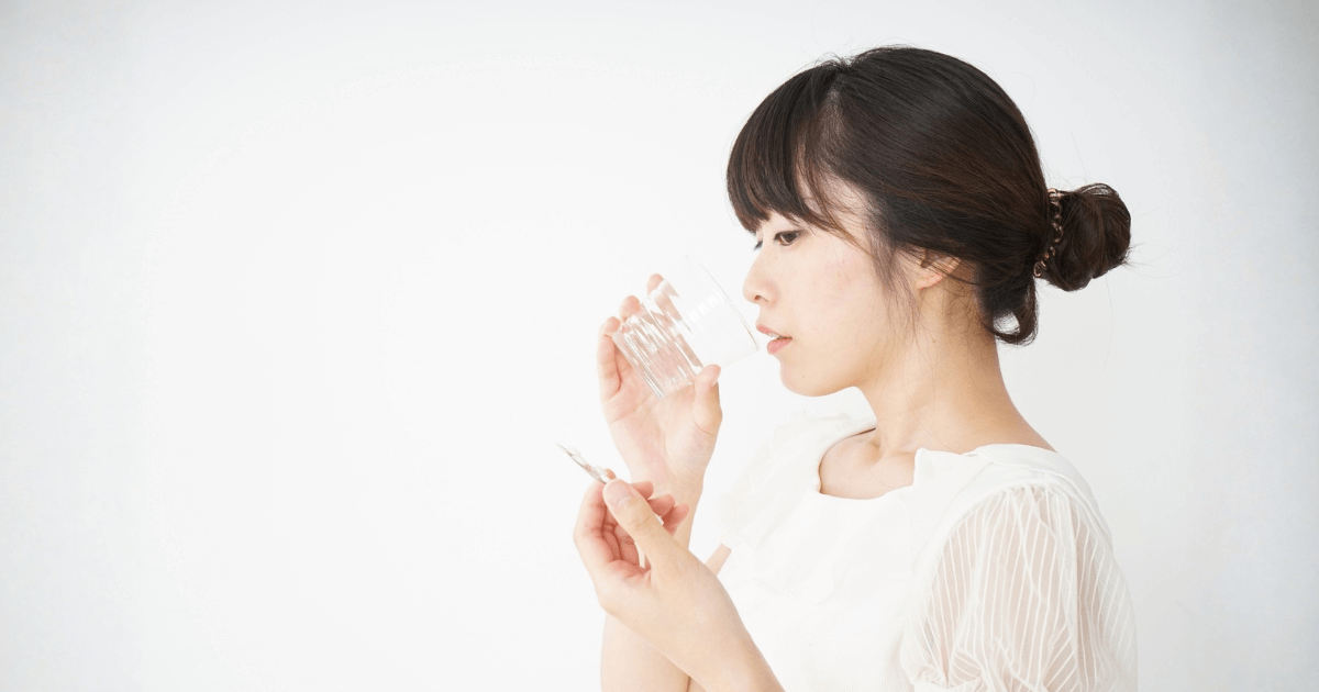 歯の痛みが続き、薬を手に取る女性。虫歯や神経の炎症、ストレスなどの原因を考えて対処しようとする様子。