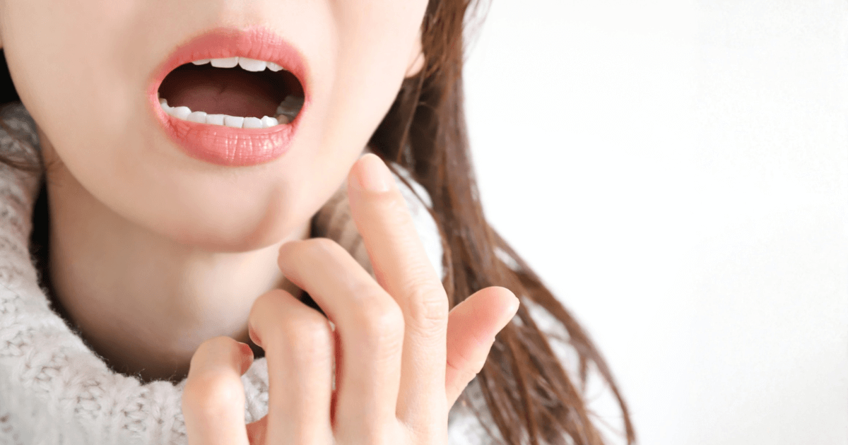 歯の痛みを感じて口元を押さえる女性。自宅でできる応急処置や痛みを和らげるケアを示すイメージ。