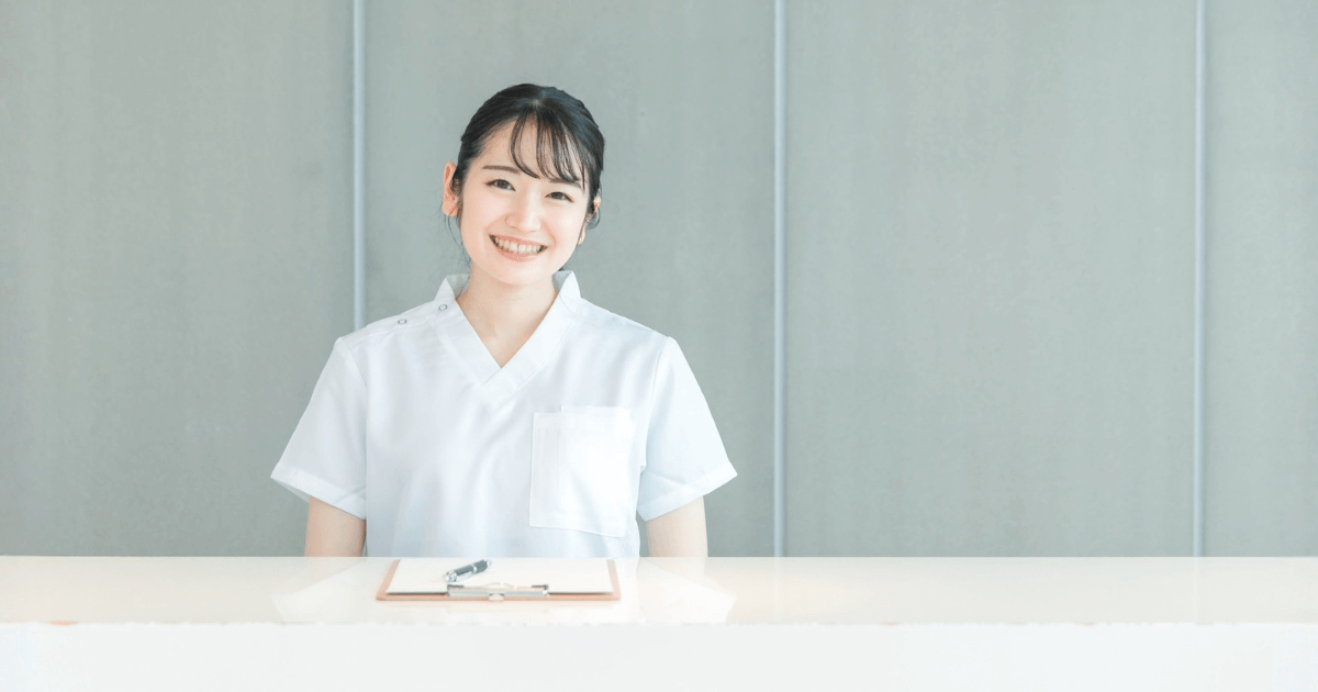 歯科医院の受付で笑顔のスタッフが案内している様子