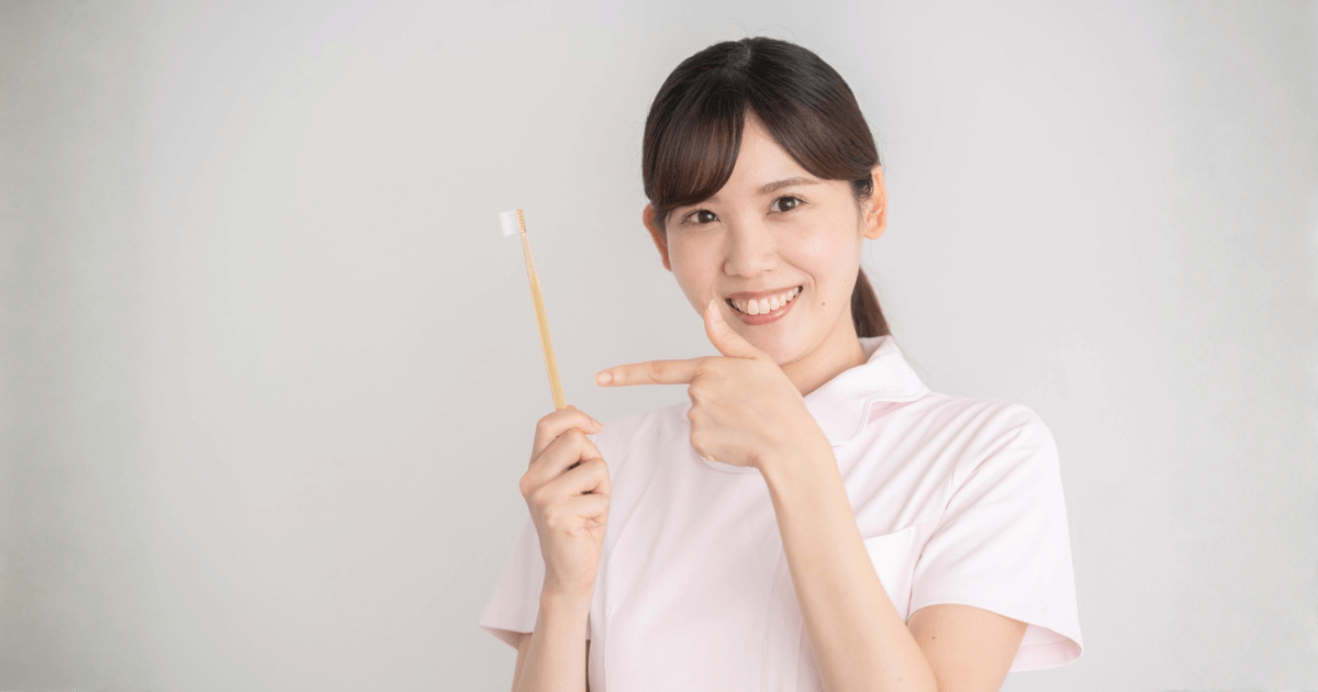 歯ブラシを手に持ち、口腔ケアの大切さを伝える歯科衛生士のイメージ。インプラント後の痛みを防ぐための正しいケアを示している。