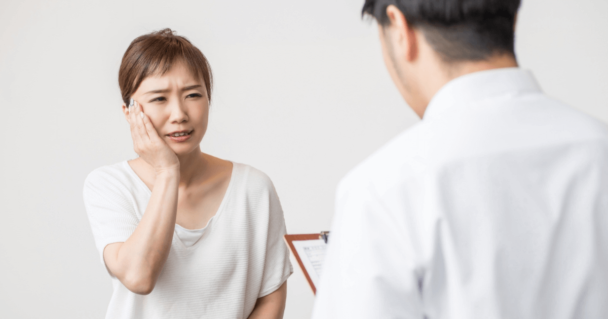 歯の痛みを訴えて歯科医に相談する女性のイメージ写真