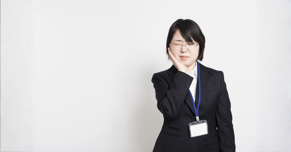 突然の歯の痛みに悩む女性が頬を押さえている様子