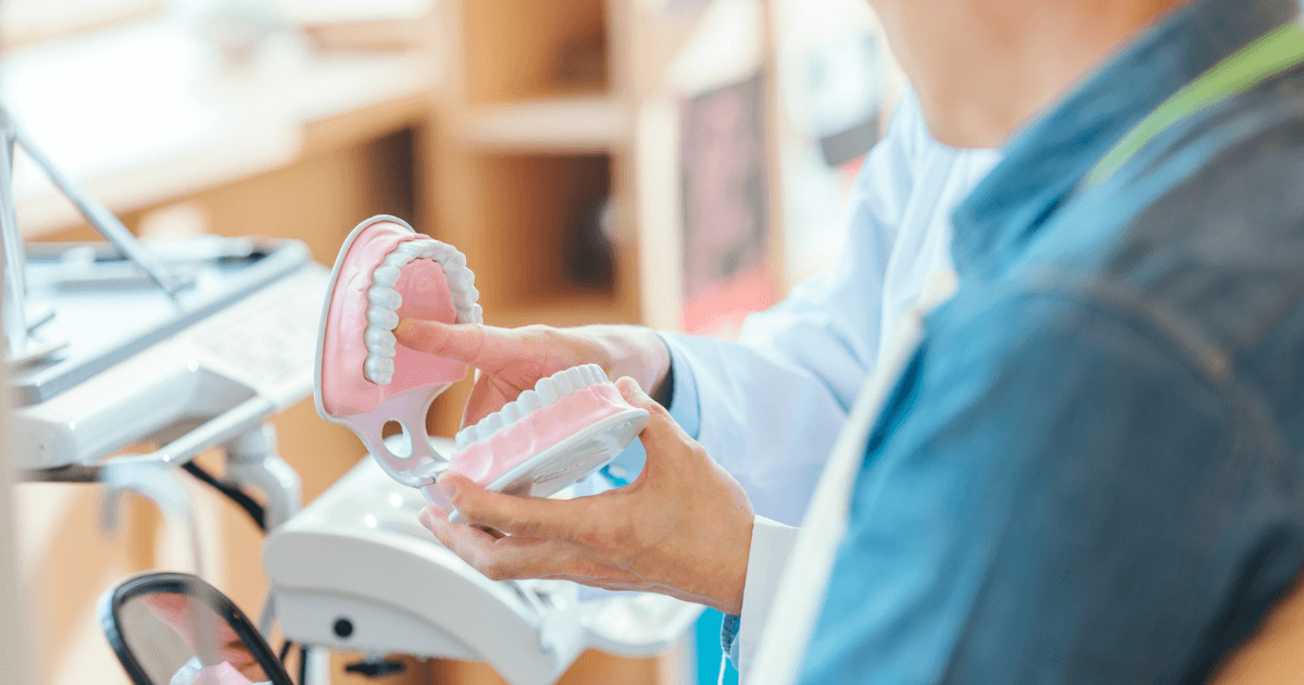 奥歯が割れた場合の治療方法や費用の違いを歯科医師が模型で説明しているイメージ画像