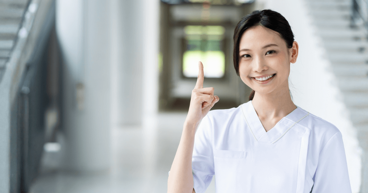 治療費を抑えるポイントを示すように指を立てる歯科スタッフ