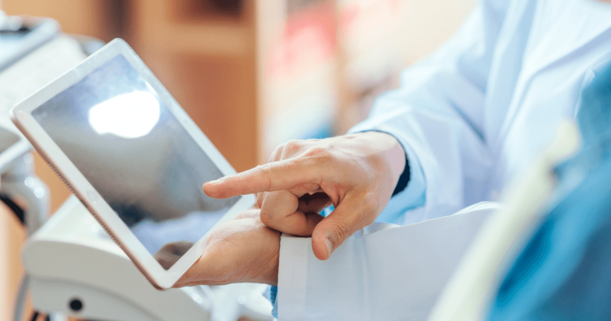 タブレットを使って治療内容を説明する歯科医師の手元