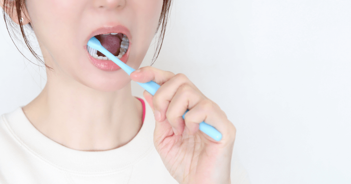 欠けた歯を刺激しないよう注意しながら歯を磨いている女性の写真