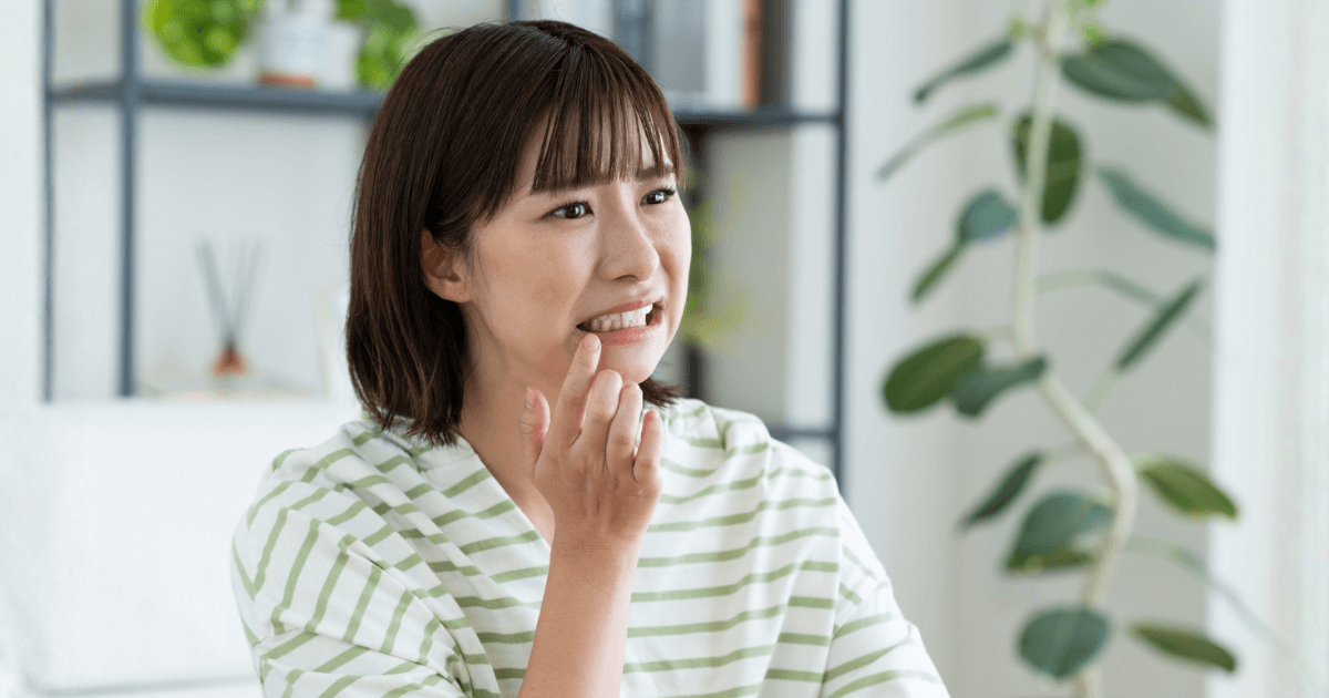 歯の痛みや欠けを放置して不安そうに口元を押さえる女性の写真
