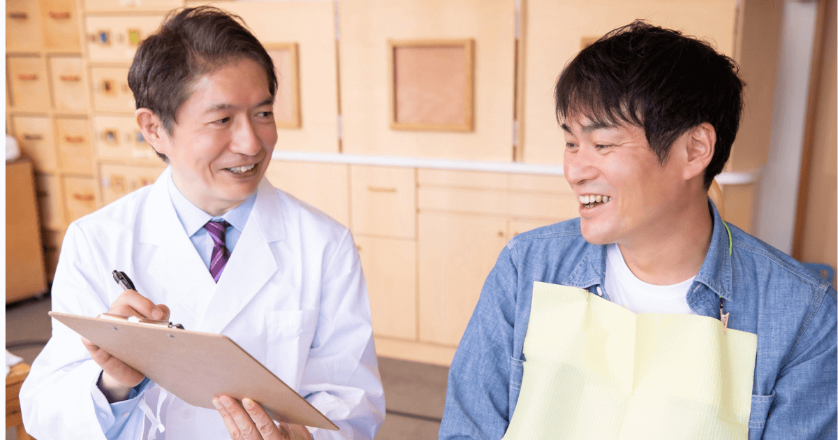 歯科医師と笑顔で相談する男性患者