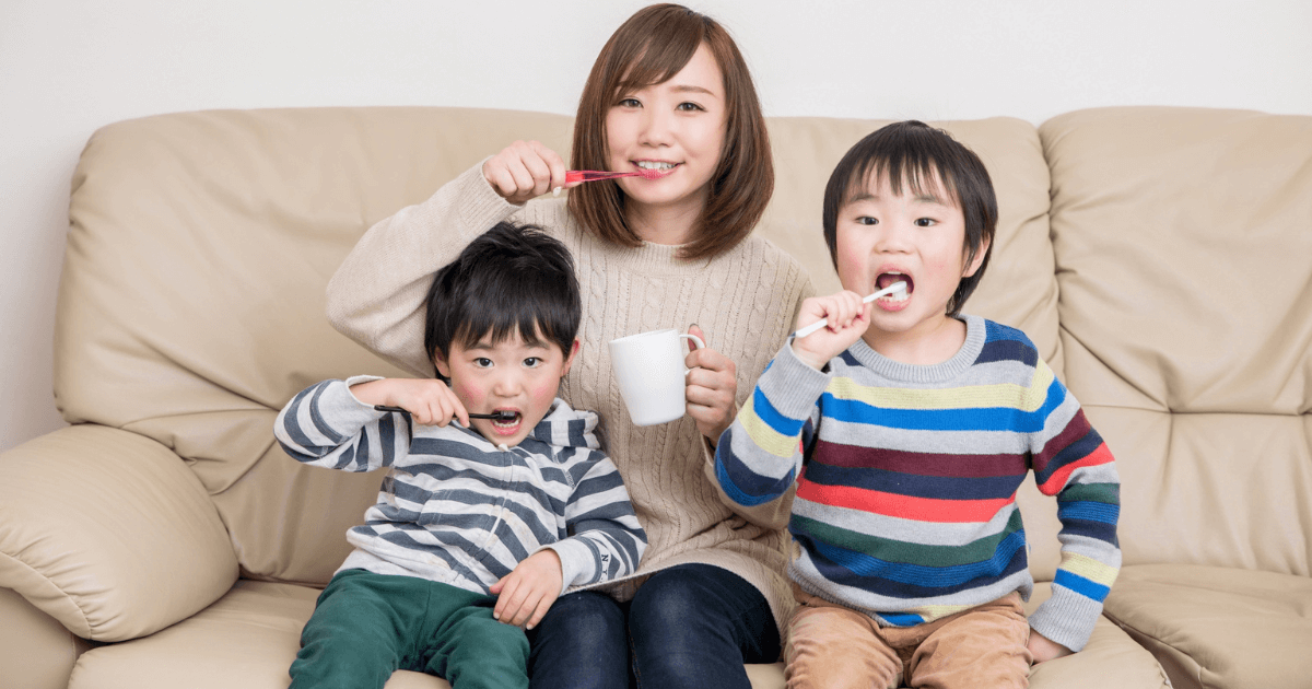 ソファに座って一緒に歯磨きをする母親と子どもたち