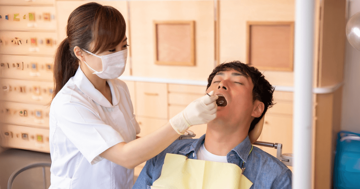 歯科検診を受けている男性と歯科衛生士の写真