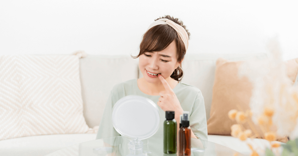 鏡を見ながら歯の黒ずみを気にする女性のイメージ