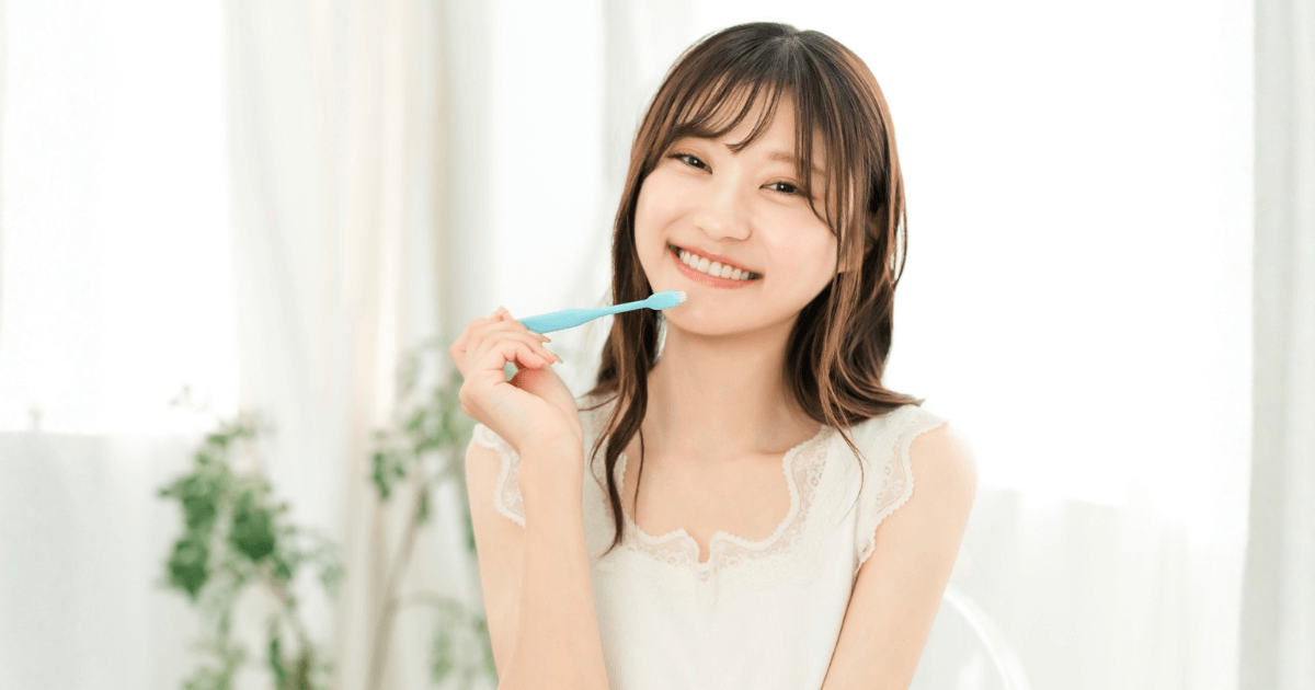 歯ブラシを持って笑顔を見せる女性の写真