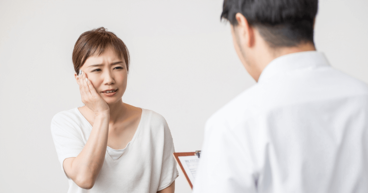歯の痛みを訴えて歯科医に相談する女性のイメージ