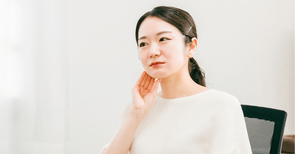 耳の前を指で押さえてツボを刺激する女性