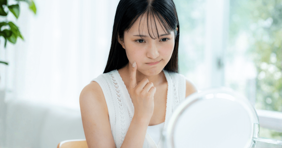 抜歯後に違和感や痛みがあり、頬に触れて症状を確認する女性のイメージ