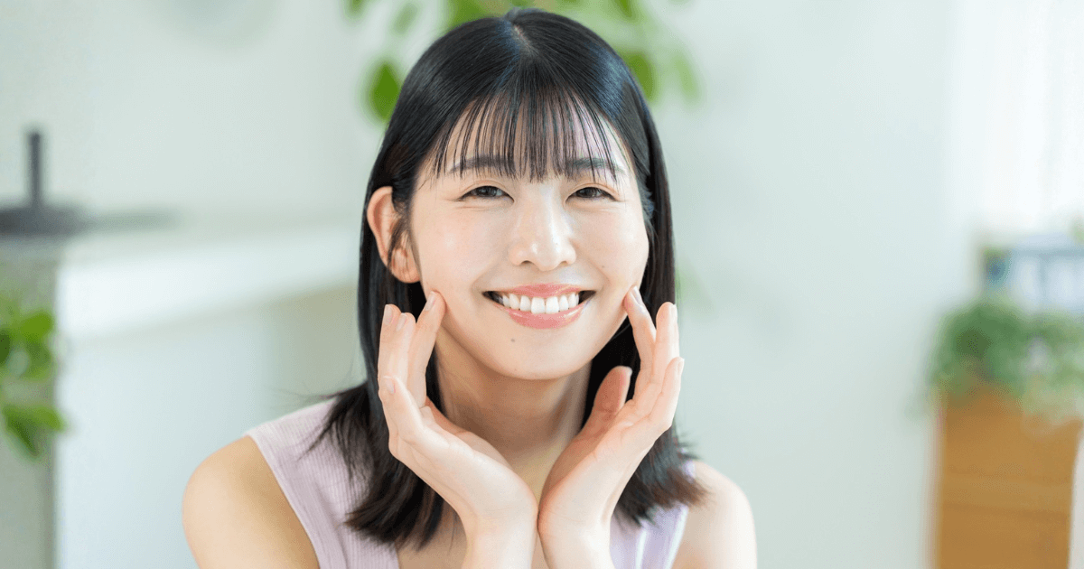 口元に手を添えて笑顔を見せる女性のアップ写真