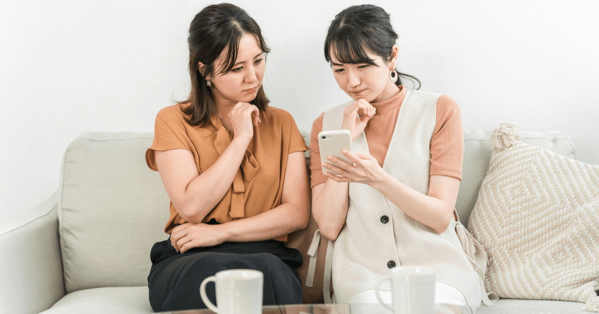 歯医者選びについてスマートフォンを見ながら相談する女性たち