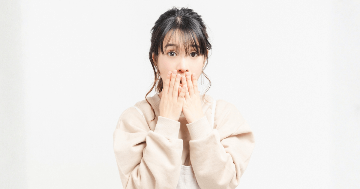 歯が欠けた原因が分からず不安そうに口元を押さえる女性の写真